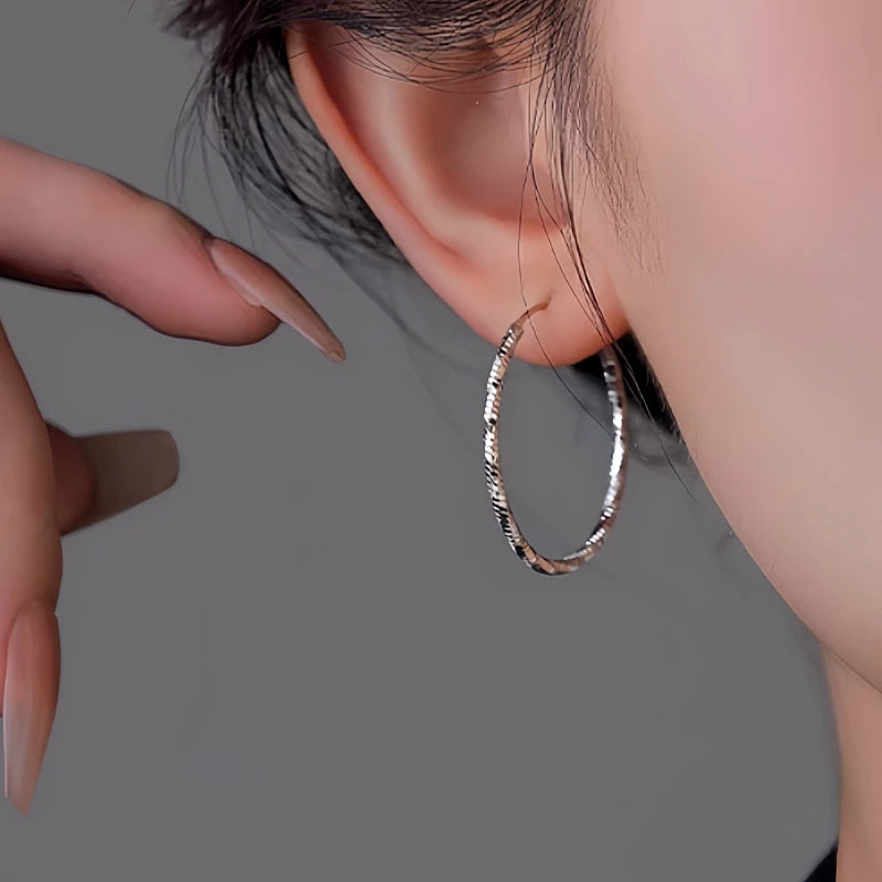 Model showcasing the dangle and style of the Sterling Silver Edge Face Hoop Earrings