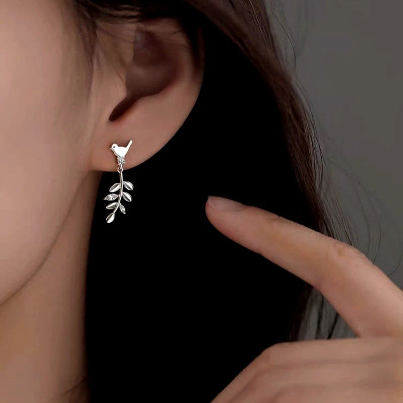 Model showcasing the dangle and style of the Sterling Silver Elegant Olive Branch Bird Earrings