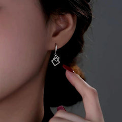 Model showcasing the dangle and style of the Sterling Silver Hollow Diamond Earrings