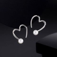 Model showcasing the dangle and style of the Sterling Silver Hollow Heart Pearl Earrings