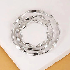 Three sizes of silver twisted wavy hoop earrings flat lay display