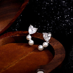 Model showcasing the dangle and style of the Sterling Silver Zircon Heart Imitation Pearl Stud Earrings