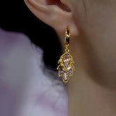 Gold leaf huggie hoop drop earring with cat's eye and purple stones worn on ear