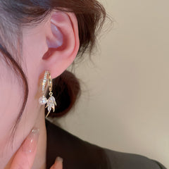 Close-up of gold pearl cubic zirconia leaf double hoop earring on woman's ear