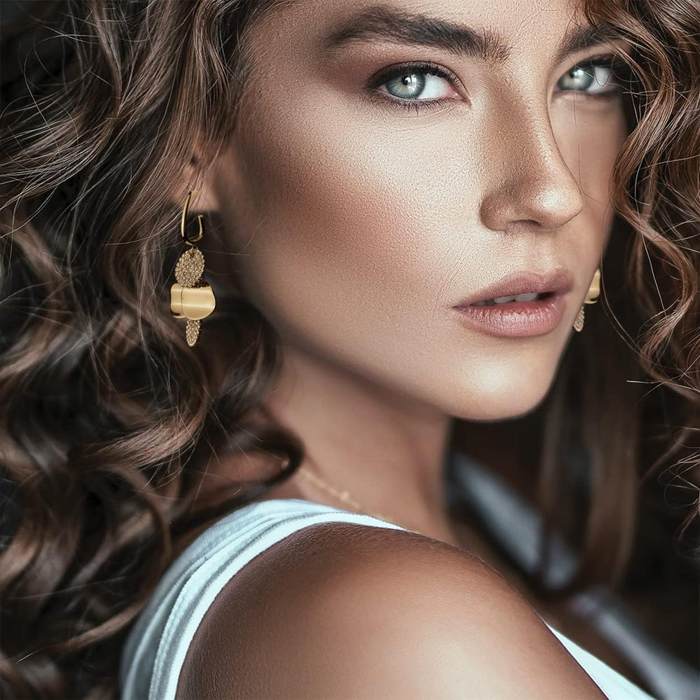 Woman with curly brown hair wearing gold pave crystal drop earrings