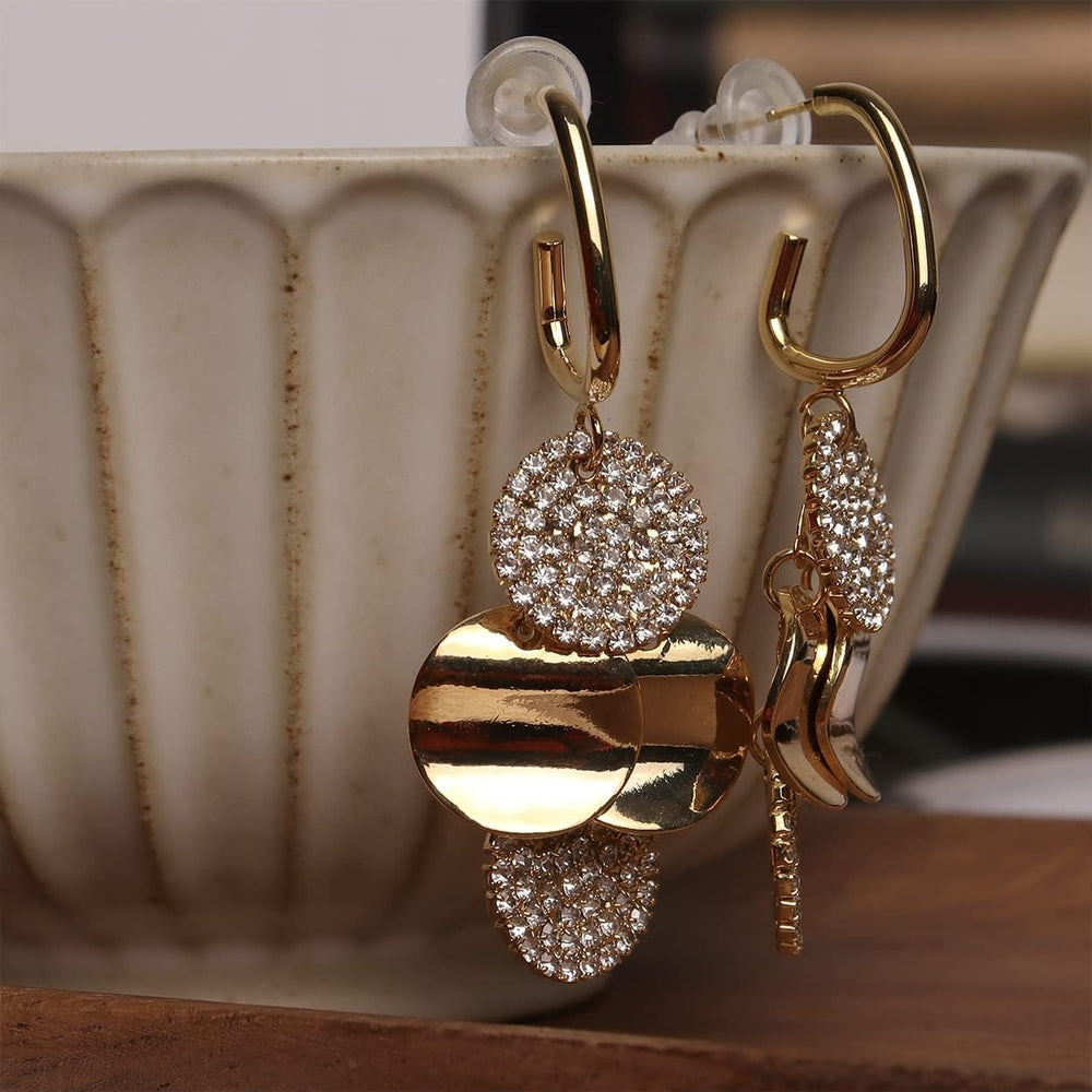 Gold pave crystal drop earrings displayed on ribbed ceramic mug edge