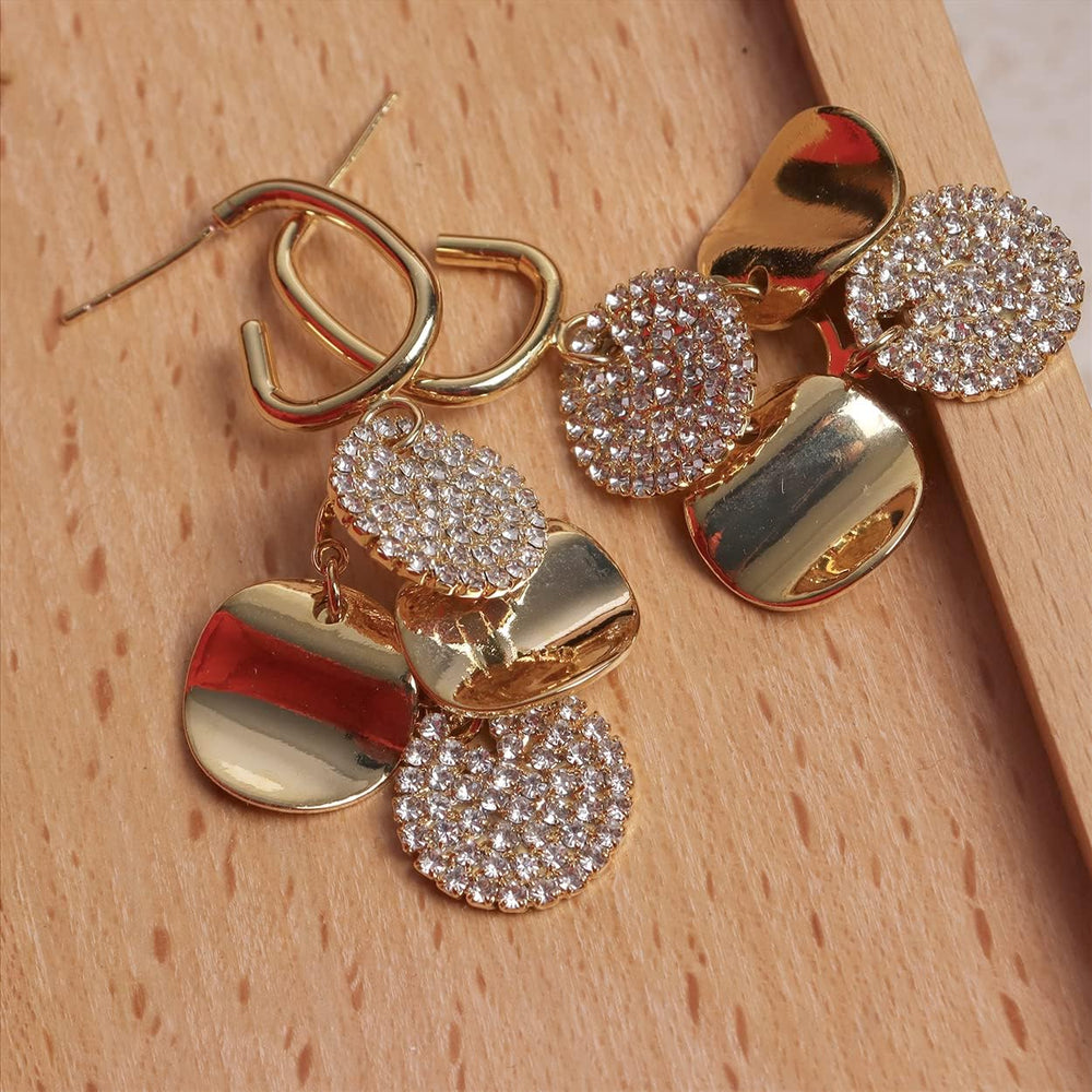 Gold geometric drop earrings with pave crystal discs on wooden surface