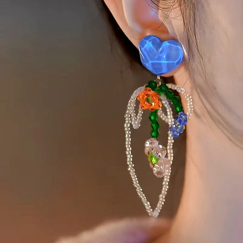 Model showcasing the dangle and style of the 14K Gold-Plated Elegant Blue Crystal Heart Bow Beaded Tassel Earrings