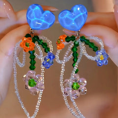 Angled view of the 14K Gold-Plated Elegant Blue Crystal Heart Bow Beaded Tassel Earrings