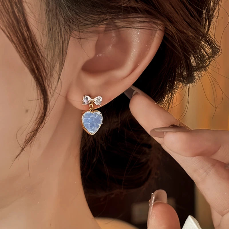 Model showcasing the dangle and style of the 14K Gold-Plated Zircon Bow Heart Earrings