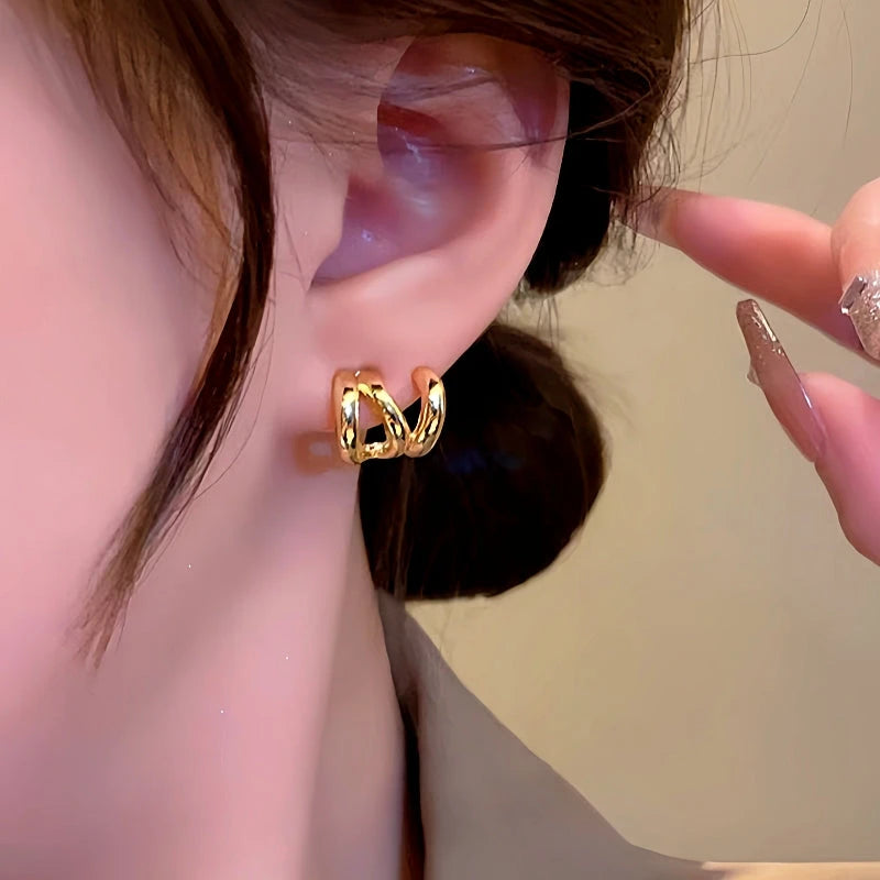 Gold twisted faux double piercing hoop earring worn on earlobe