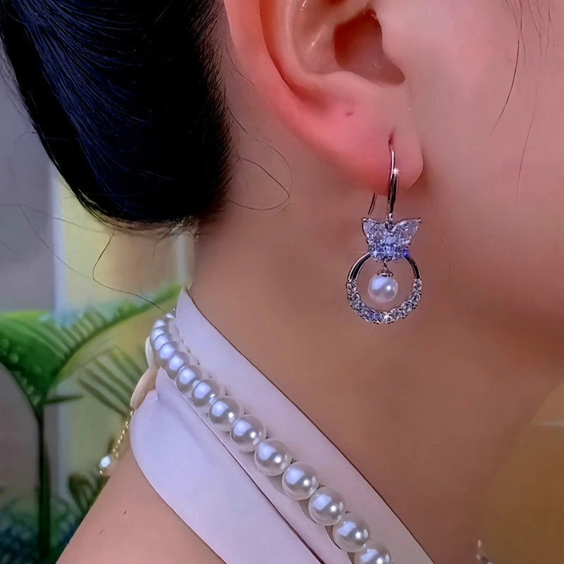 Model showcasing the dangle and style of the 14K Gold-Plated Zircon Butterfly Pearl Ear Hook Earrings