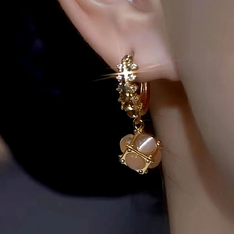 Model showcasing the dangle and style of the 14K Gold-Plated Coffee-Colored Cat's Eye Ball Earrings