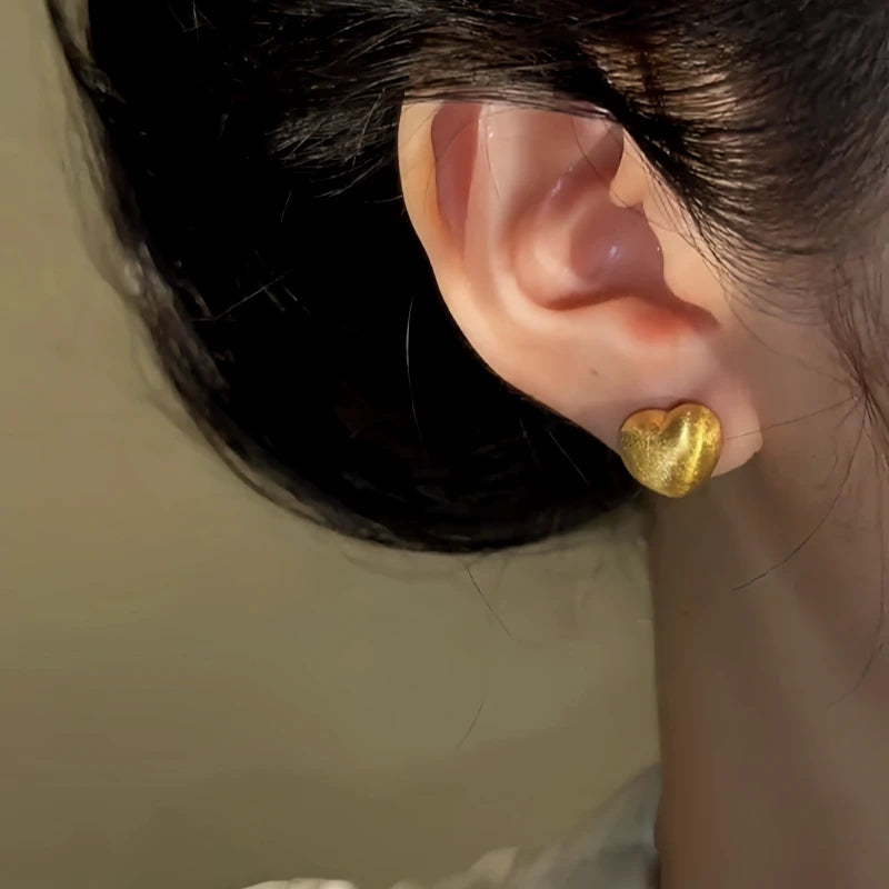 Close-up detail of the sparkling zircons and plating on the gold heart earrings