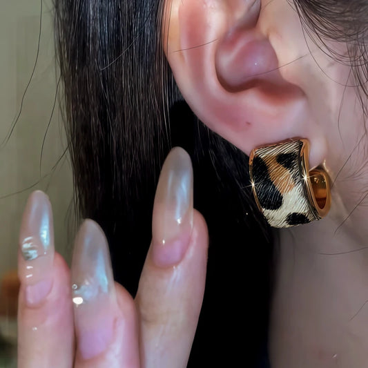 Model showcasing the dangle and style of the 14K Gold-Pated Leopard Print C-Shaped Hoop Earrings