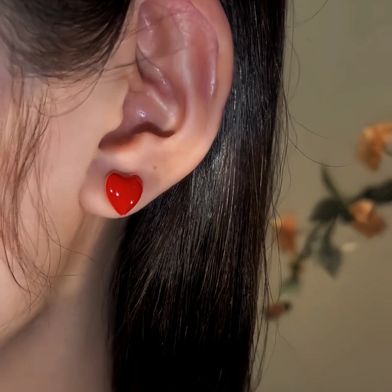 Model showcasing the dangle and style of the 14K Gold-Pated Red Heart Bead Tassel Earrings