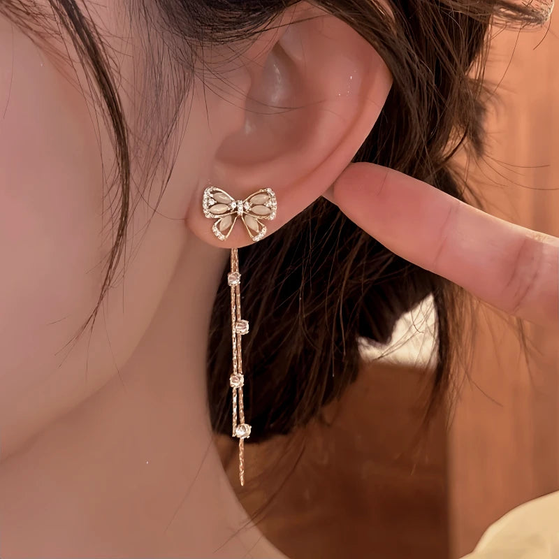 Model showcasing the dangle and style of the 14K Gold-Pated Zircon Bow Tassel Earrings