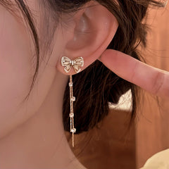 Model showcasing the dangle and style of the 14K Gold-Pated Zircon Bow Tassel Earrings