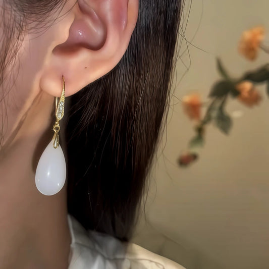 Model showcasing the dangle and style of the 14K Gold-Pated Zircon White Jade Drop Earrings