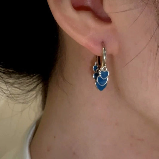 Model showcasing the dangle and style of the 14K Gold-Plated And Sterling Silver Blue Heart Tassel Earrings