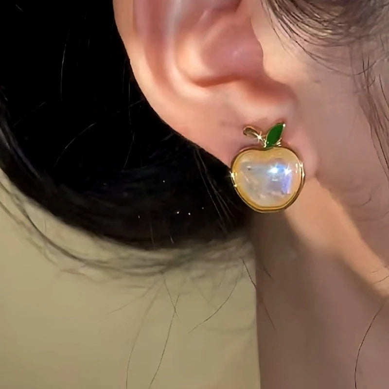 Model showcasing the dangle and style of the 14K Gold-Plated Apple Stud Earrings