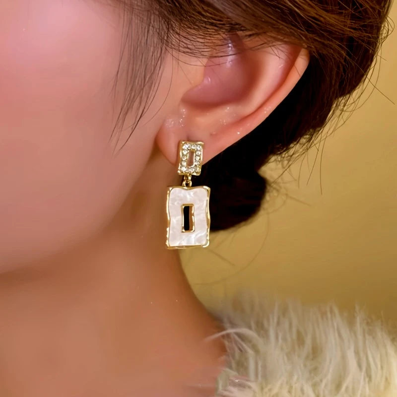 Model showcasing the dangle and style of the 14K Gold-Plated Asymmetrical Square Earrings