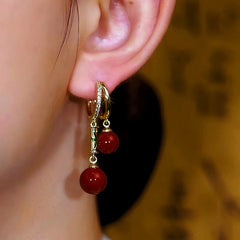 Model showcasing the dangle and style of the 14K Gold-Plated Bamboo Red Pearl Earrings