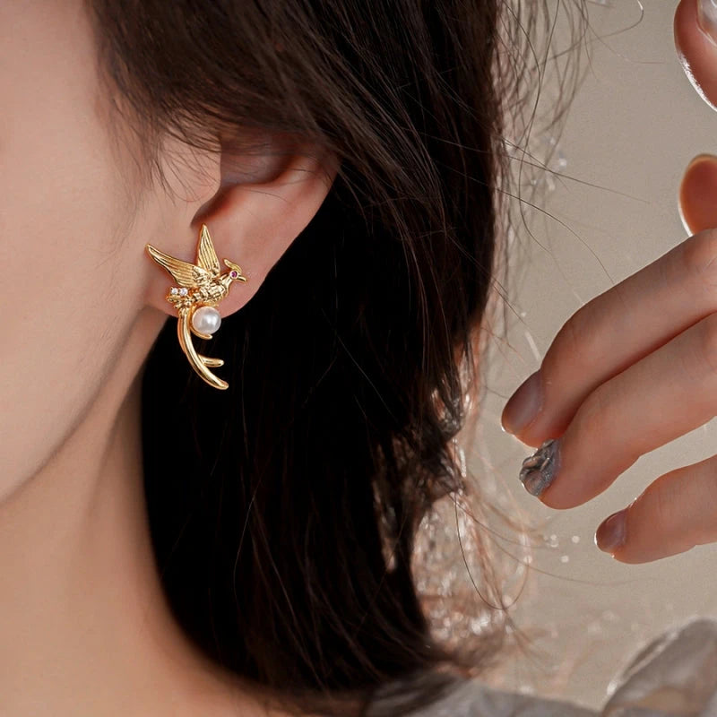 Model showcasing the dangle and style of the 14K Gold-Plated Bird Pearl Stud Earrings
