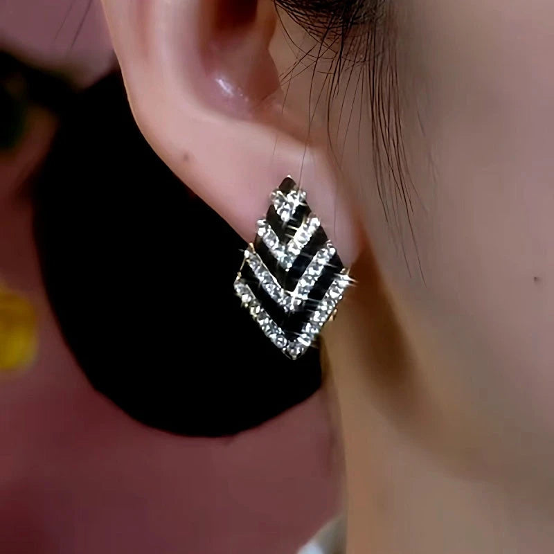 Model showcasing the dangle and style of the 14K Gold-Plated Black And White Diamond Earrings