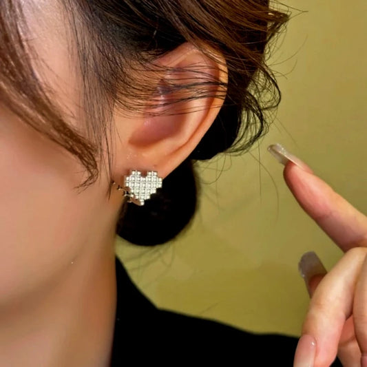 Model showcasing the dangle and style of the 14K Gold-Plated Black And White Diamond Heart Earrings