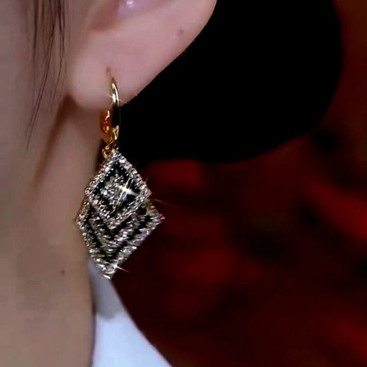Model showcasing the dangle and style of the 14K Gold-Plated Black And White Diamond Tassel Earrings