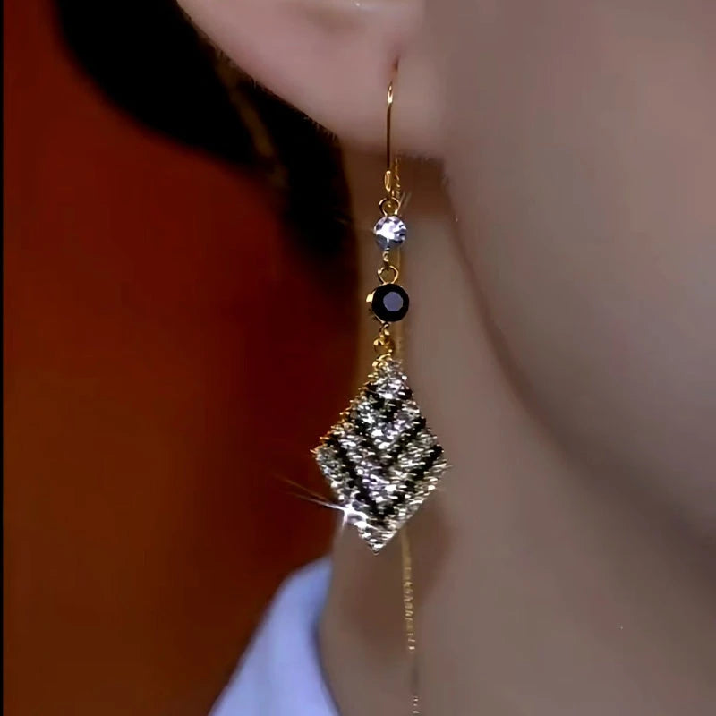 Model showcasing the dangle and style of the 14K Gold-Plated Black And White Diamond Threader Tassel Earrings