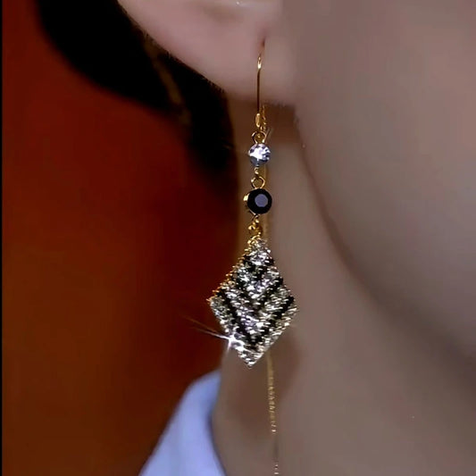Model showcasing the dangle and style of the 14K Gold-Plated Black And White Diamond Threader Tassel Earrings