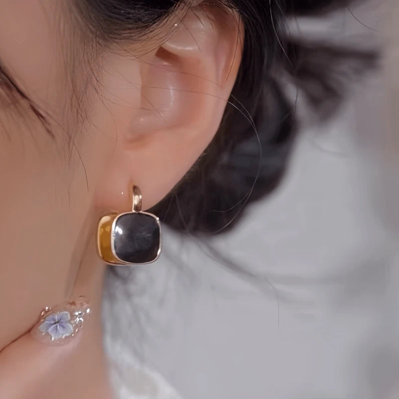 Model showcasing the dangle and style of the 14K Gold-Plated Black And White Double-Sided Earrings