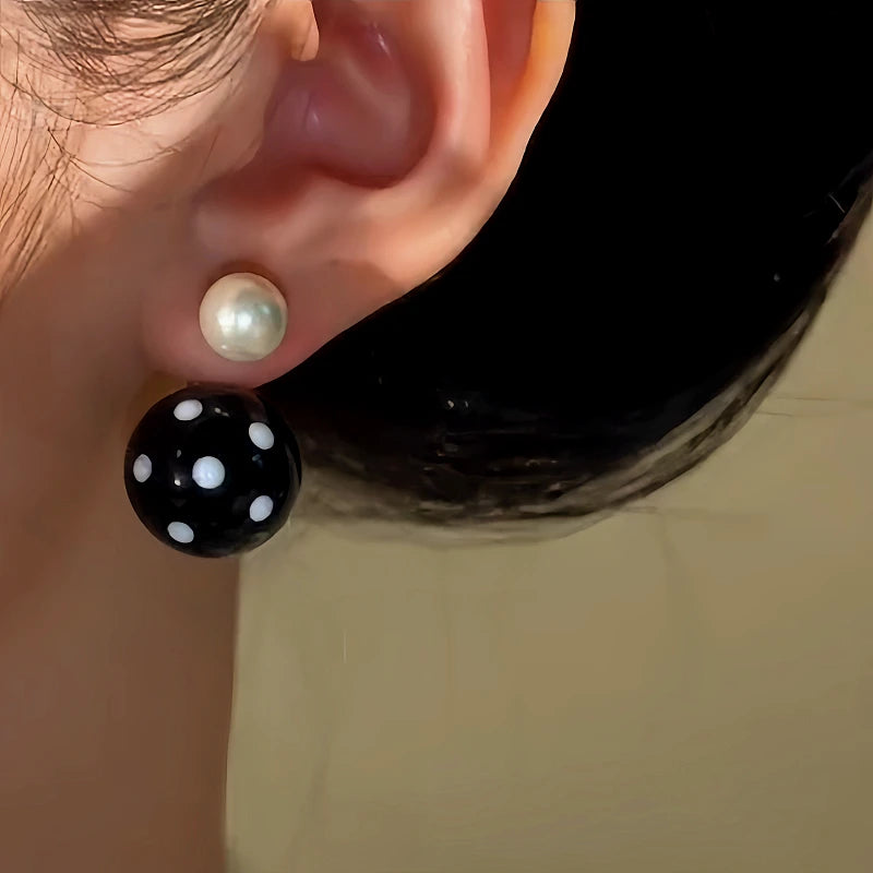 Model showcasing the dangle and style of the 14K Gold-Plated Black And White Polka Dot Pearl Earrings