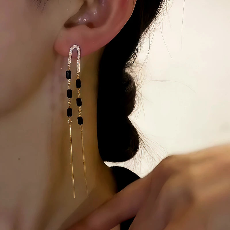 Model showcasing the dangle and style of the 14K Gold-Plated Black Crystal Long Tassel Earrings