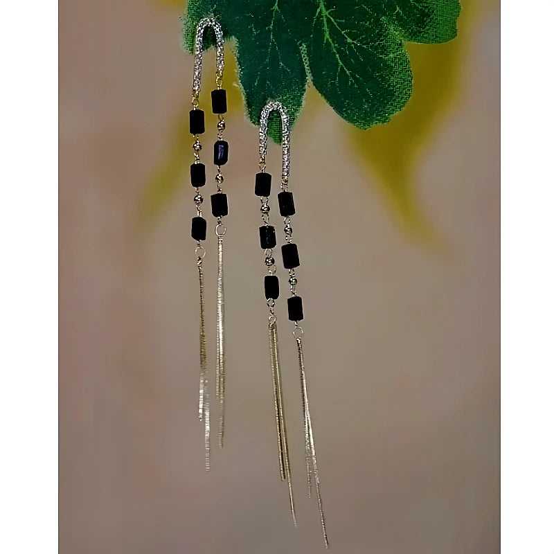 Angled view of the 14K Gold-Plated Black Crystal Long Tassel Earrings