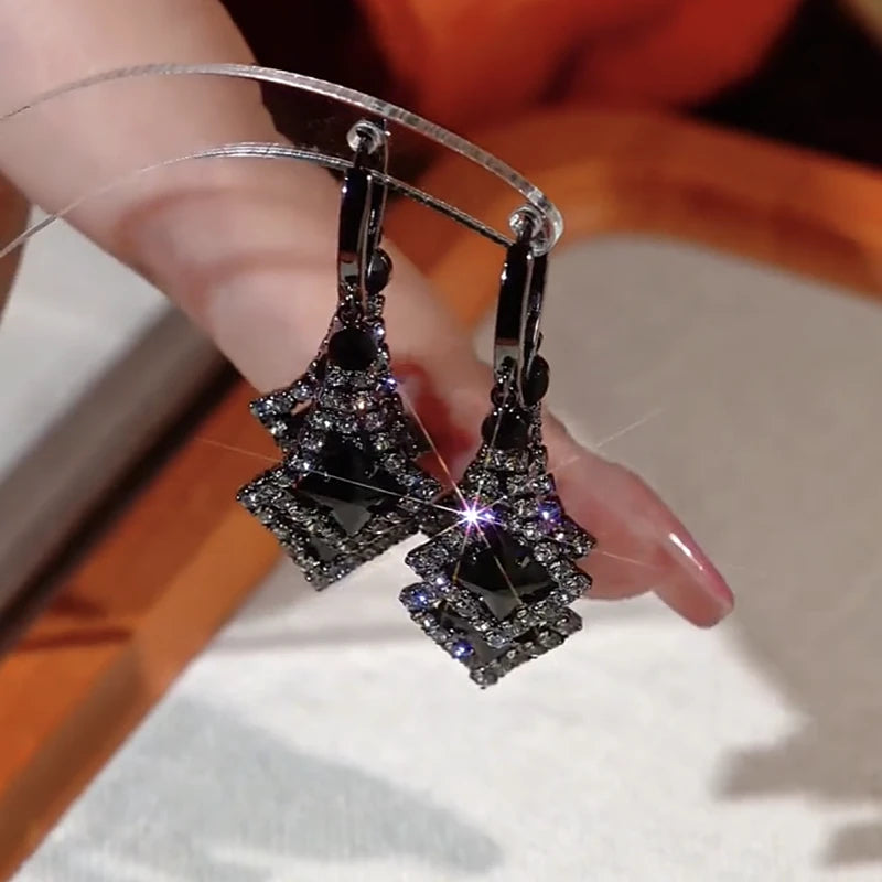 Angled view of the 14K Gold-Plated Black Crystal Tassel Earrings