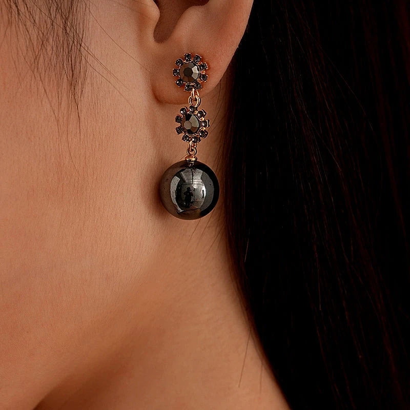 Model showcasing the dangle and style of the 14K Gold-Plated Black Diamond Flower Ball Earrings