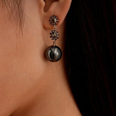 Model showcasing the dangle and style of the 14K Gold-Plated Black Diamond Flower Ball Earrings
