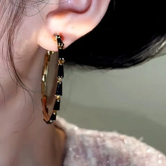 Model showcasing the dangle and style of the 14K Gold-Plated Black Zircon Hoop Earrings