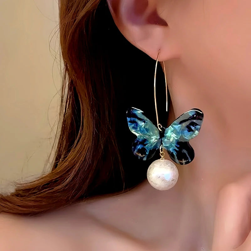 Model showcasing the dangle and style of the 14K Gold-Plated Blue Butterfly Pearl Pendant Ear Hook Earrings