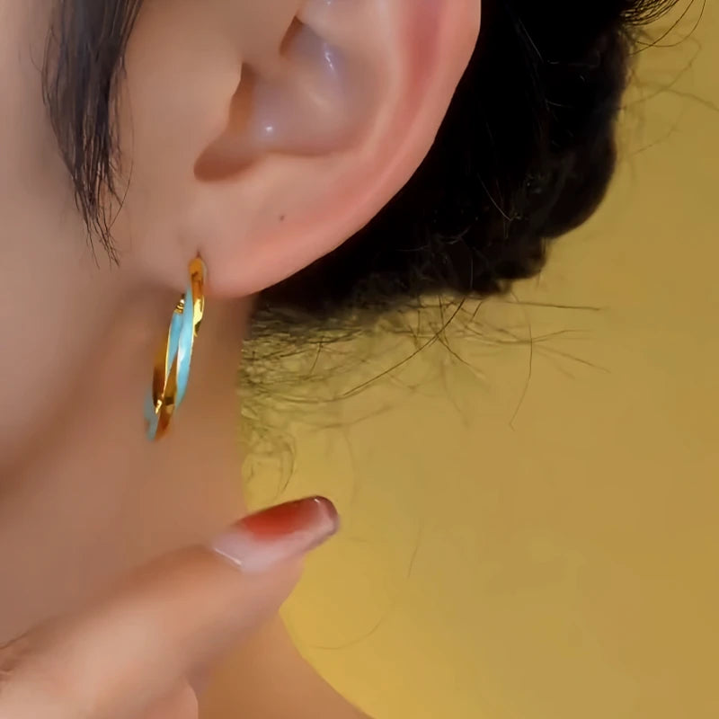 Model showcasing the dangle and style of the 14K Gold-Plated Blue Oil Drop Hoop Earrings