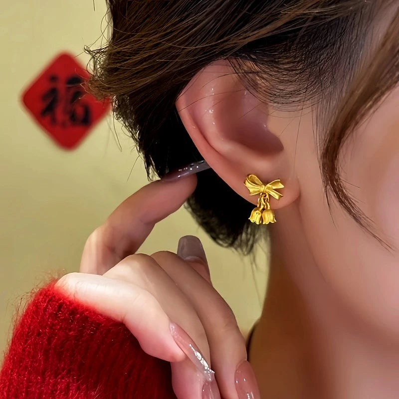 Model showcasing the dangle and style of the 14K Gold-Plated Bow Orchid Flower Earrings