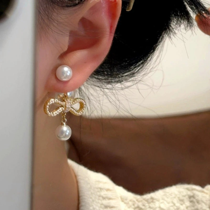 Model showcasing the dangle and style of the 14K Gold-Plated Bow Pearl Earrings