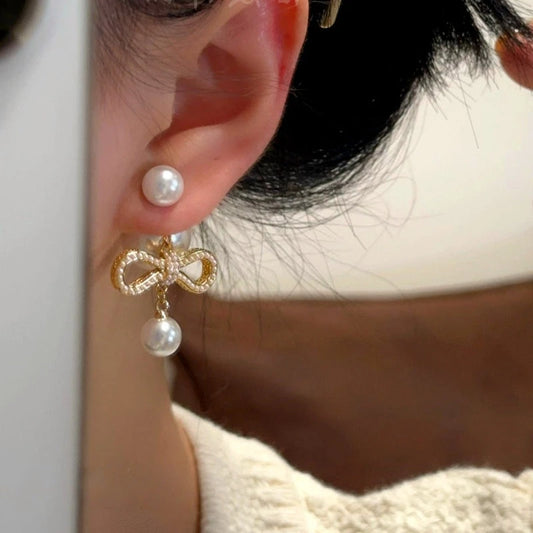 Model showcasing the dangle and style of the 14K Gold-Plated Bow Pearl Earrings