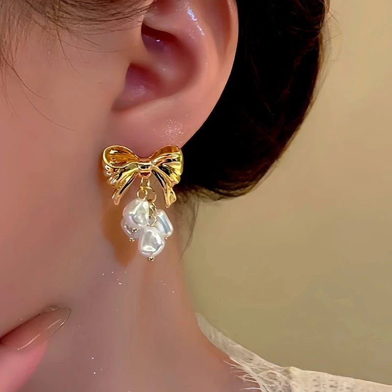 Model showcasing the dangle and style of the 14K Gold-Plated Bow Pearl Tassel Earrings
