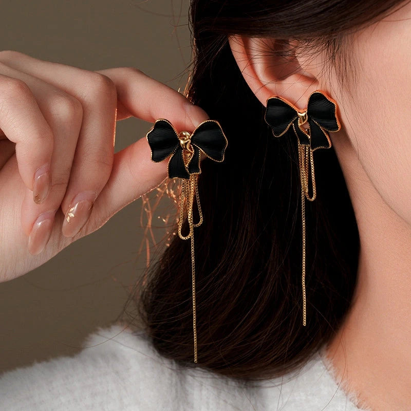 Model showcasing the dangle and style of the 14K Gold-Plated Bow Tassel Earrings