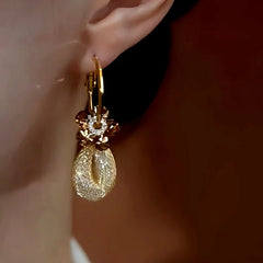 Model showcasing the dangle and style of the 14K Gold-Plated Brown Crystal Flower Mesh Earrings