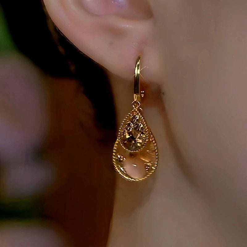 Model showcasing the dangle and style of the 14K Gold-Plated Brown Crystal Water Drop Earrings